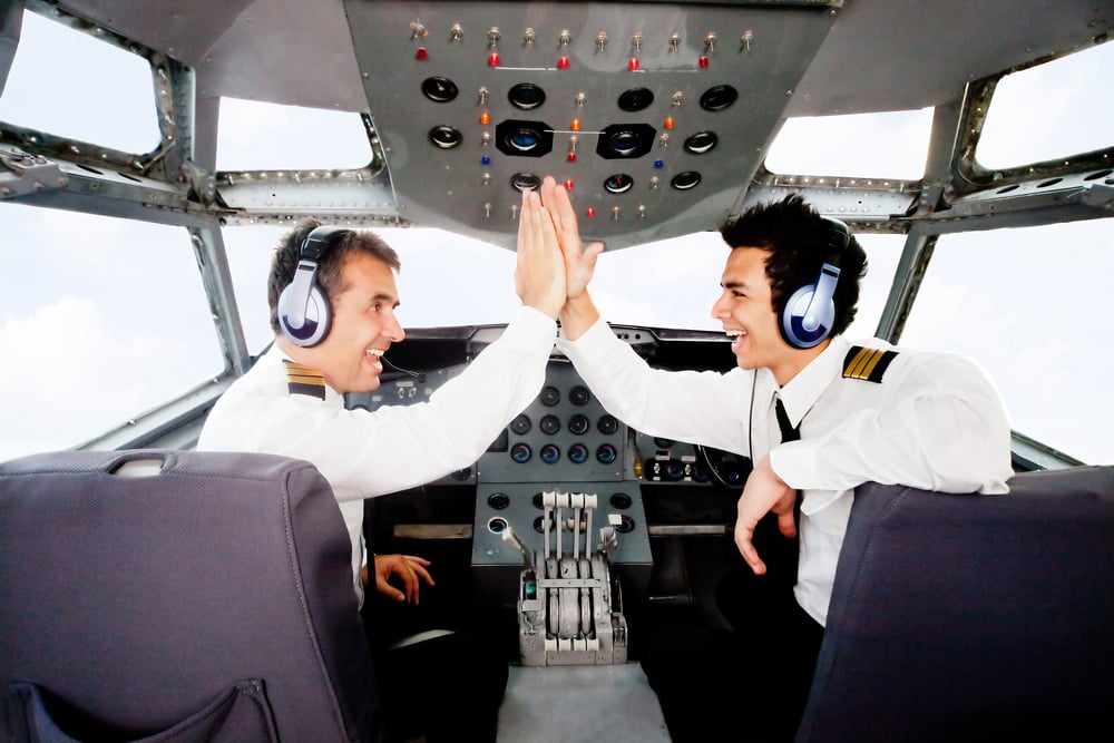 Pilots giving a high-five in an airplane cabin